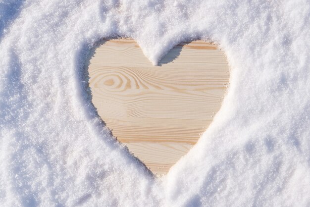 Heart shape on the wooden table made of snow