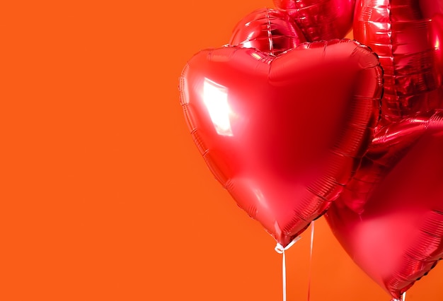 Heart shaped air balloons on orange background