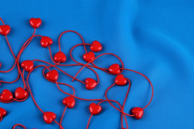 Heart-shaped beads on string on fabric background