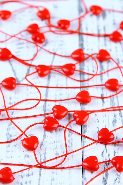 Heart-shaped beads on string on wooden background