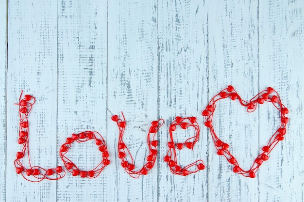 Heart-shaped beads on string on wooden background