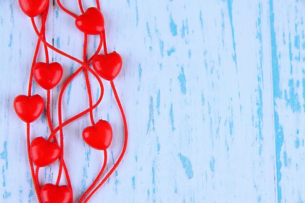 Heart-shaped beads on string on wooden background