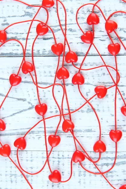 Heart-shaped beads on string on wooden background