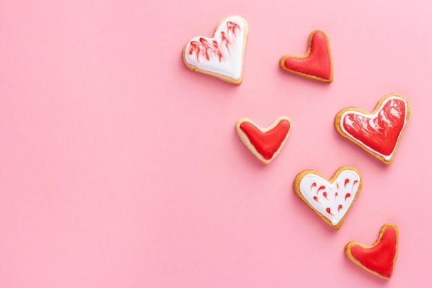 Heart shaped biscuits glazed with sugar icing for St Valentine day on pink background