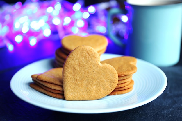 Heart shaped biscuits on plate and mug on a table