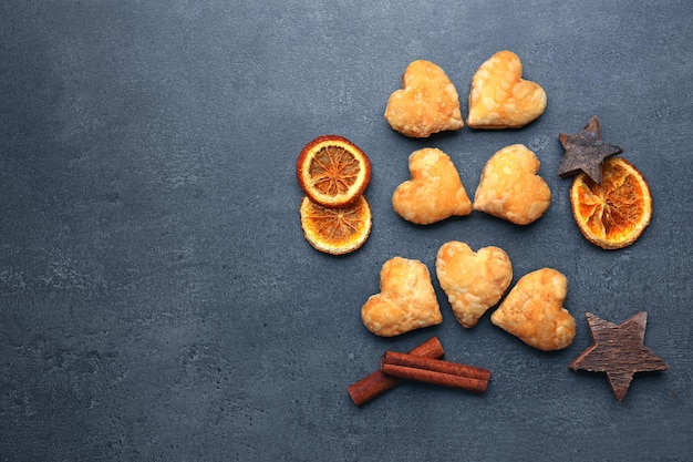 Biscotti a forma di cuore con spezie essiccate su fondo grigio scuro