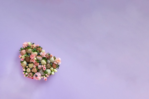 Коробка в форме сердца с клубникой в шоколаде ручной работы с разными начинками и цветами в подарок на день Святого Валентина на фиолетовом фоне со свободным пространством для текста