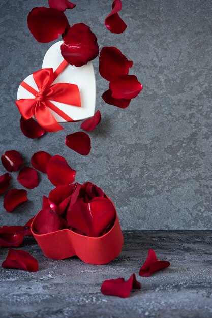 Heart shaped box with red petals on dark background