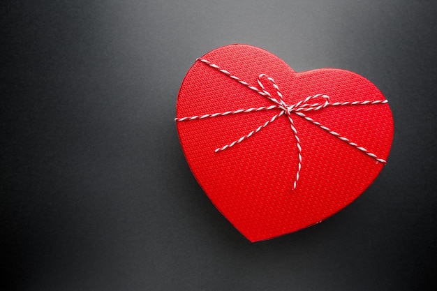 Heart shaped cardboard gift box with bow on black background