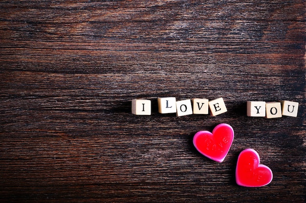 Heart shaped chewing candies and words I love you on cubes wooden background Free space for your text