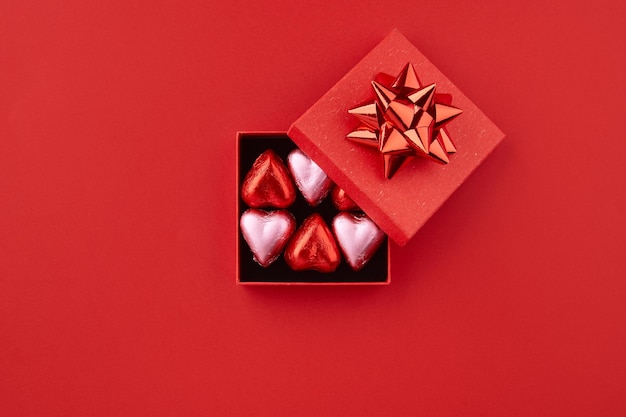 Heart shaped chocolate candies in red gift box on the red background