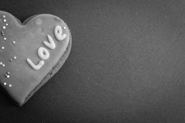 Heart shaped cookie on black background, black and white. Sweet heart cookie. Unhappy love.