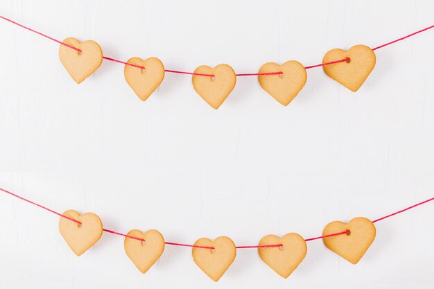 Heart shaped cookies hanging on a white wall. Symbol of cozy love and Valentines Day background and festive concept