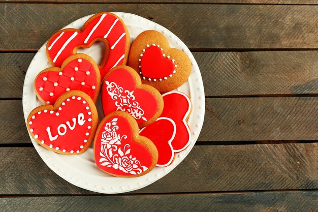 木製の背景に、プレート上のバレンタインデーのためのハート型のクッキー