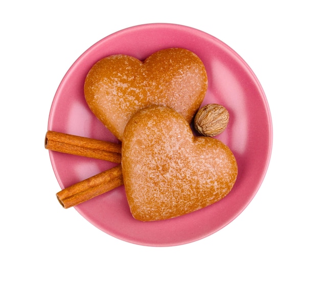 Heart-shaped cookies with cinnamon and nutmeg on saucer isolated on white