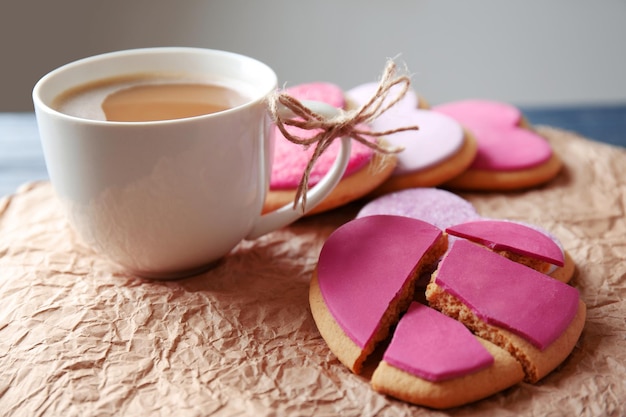 Heart shaped cookies with cup of coffee and parchment closeup