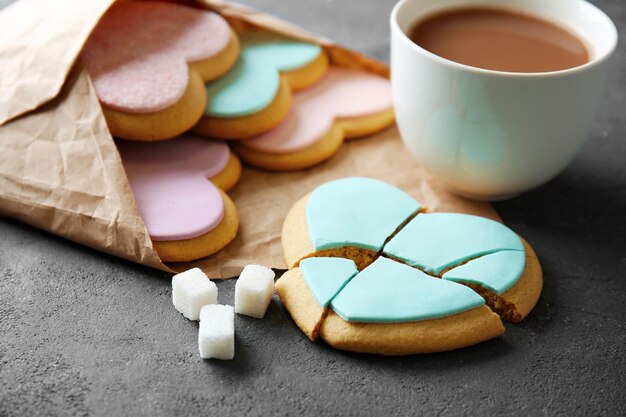 Heart shaped cookies with cup of coffee and parchment on grey background closeup