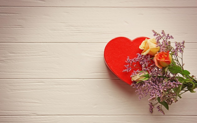 Heart shaped gift box with flowers on wooden table