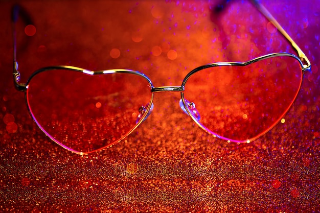 Heart-shaped glasses on a red background with bokeh. The Valentine's Day concept