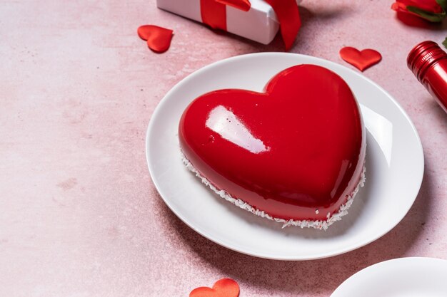 Photo heart shaped glazed valentine cake gift and wine on pink concrete background