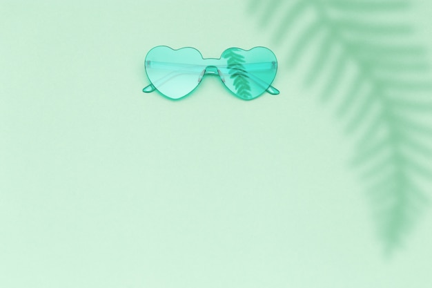 Heart shaped green glasses on paper surface with shadow