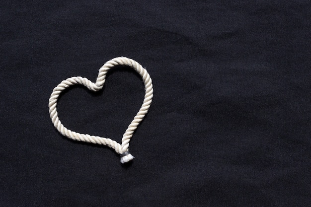 Foto un nodo a forma di cuore fatto di corda bianca. concetto di amore.