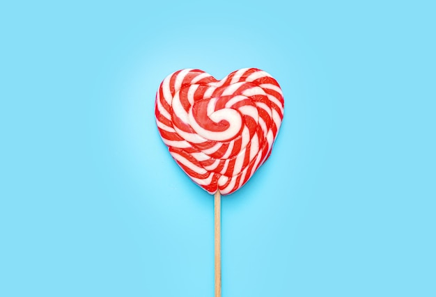 Heart shaped lollipop over blue background