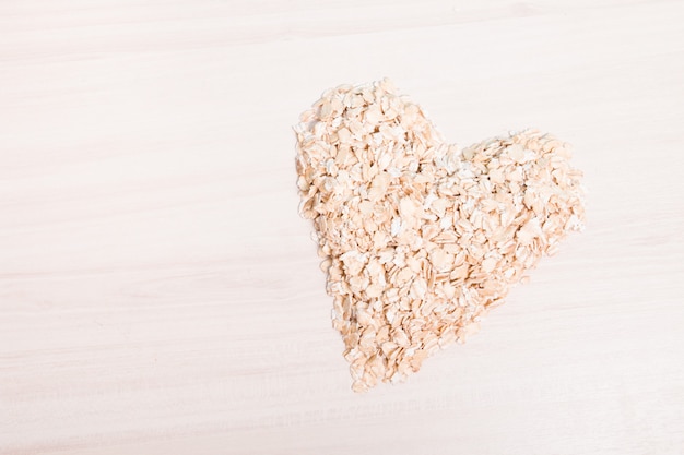 Heart-shaped oatmeal on a wooden table, copy space, top view