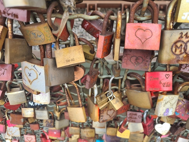 A heart shaped padlock is hanging on a bridge.