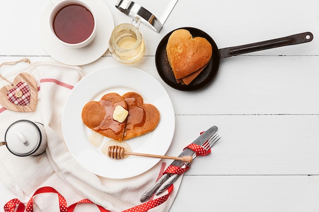 写真 明るい背景にハート型のパンケーキ、バレンタインデーのお祝いの朝食や愛する人への楽しいサプライズのコンセプト