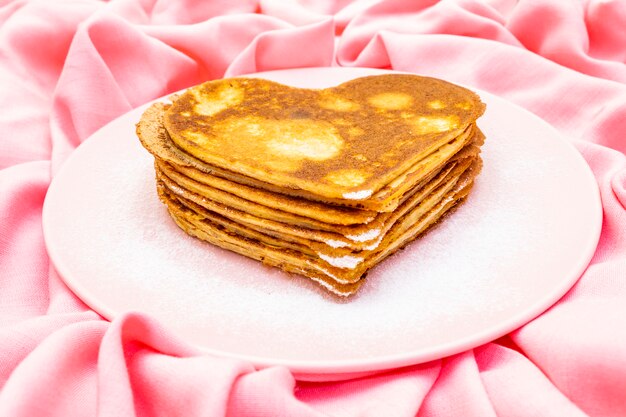 Heart shaped pancakes for romantic breakfast on rosy plate