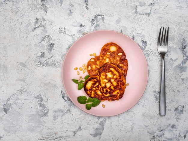 Heart shaped pancakes with mint and powdered sugar on pink plate top view