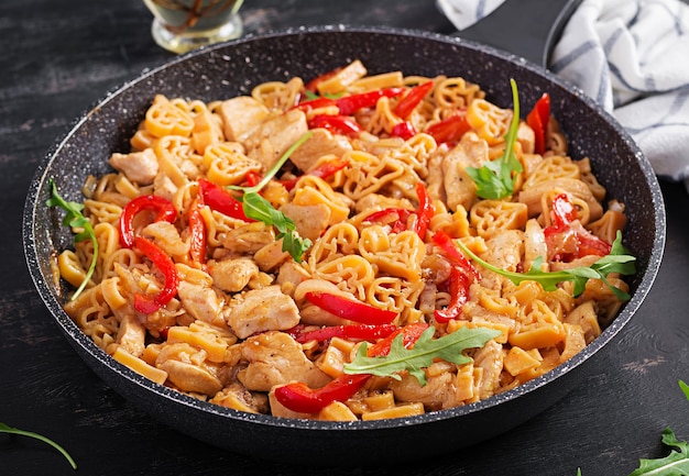 Heart-shaped pasta  in tomato sauce with chicken and sweet pepper with arugula. Background, texture