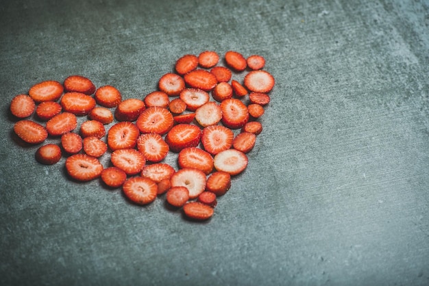 Heart shaped pieces of strawberries over grey concrete background