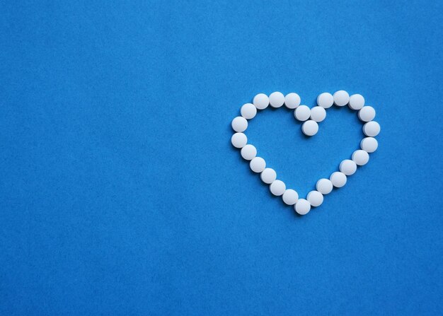 Heart shaped pills on a blue background