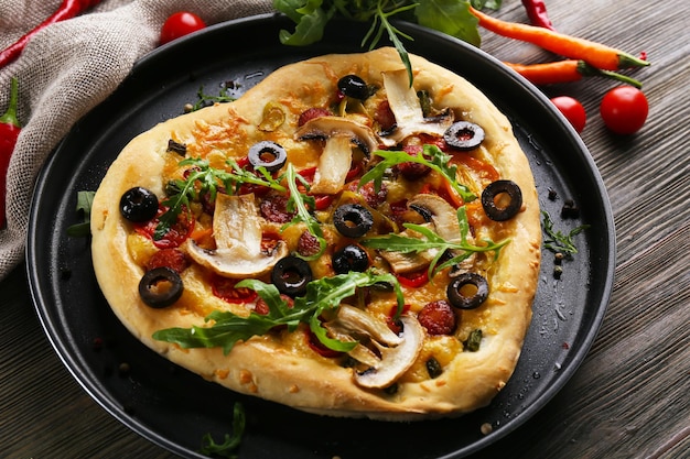 Heart shaped pizza on metal tray on wooden background