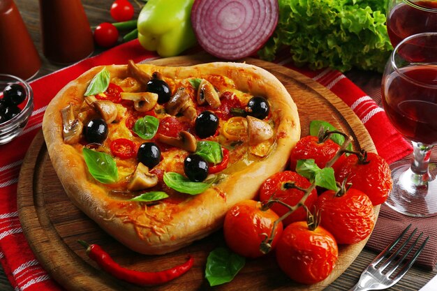 Heart shaped pizza served on wooden table, closeup