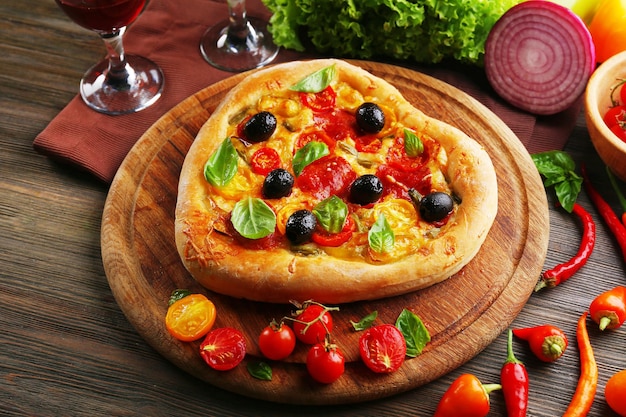 Heart shaped pizza served on wooden table, closeup