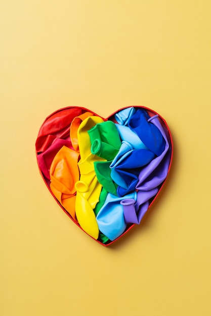 Heart shaped rainbow lgbtq flag against yellow background pride month