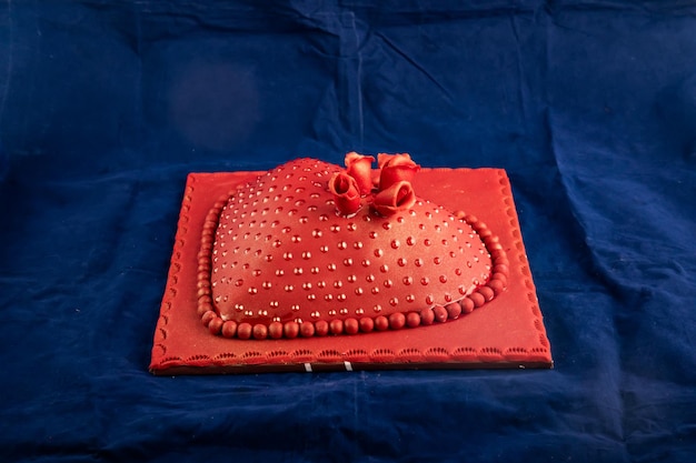 Красный торт в форме сердца с ножом и вилкой из розовых цветов, подаваемый на борту, изолированный на салфетке, вид сбоку на выпечку в кафе