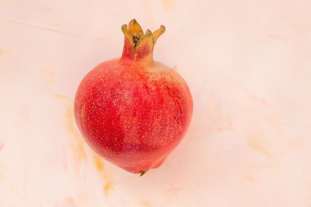 A heart shaped red ripe pomegranate on pink background