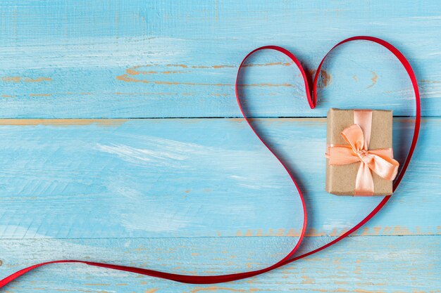 Heart shaped ribbon and gift box on a blue wooden table. Valentine's Day Gift