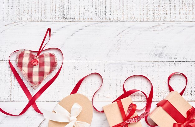 Heart shaped ribbon and gift box over white wooden table background with copy space. Valentine day greeting card.