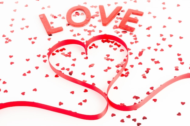 heart shaped ribbon with confetti and word love