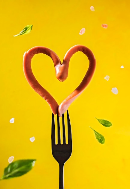 Foto salsiccia a forma di cuore su una forchetta colazione con amore