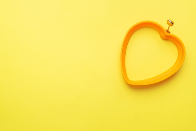 Stampo in silicone a forma di cuore per cuocere e friggere uova su fondo giallo. vista dall'alto, minimalista, copia spazio.