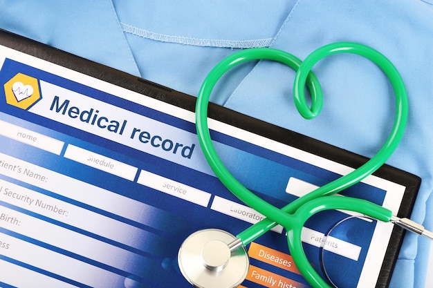 Photo heart shaped stethoscope with medical record on blue uniform close up