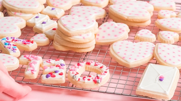 Heart shaped sugar cookies decorated with royal icing on drying rack.