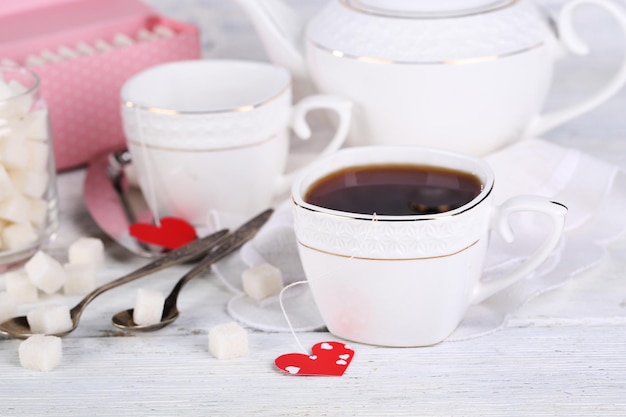 Heart shaped teabag tags, box and teapot on wooden background