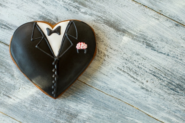 Heart shaped tuxedo biscuit. Dark colored wedding cookie. Feel the taste of holiday. Symbol of new beginning.